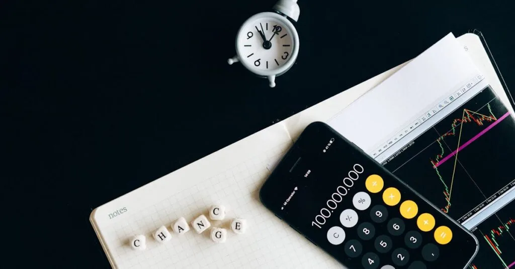 Notebook with an iPhone displaying 100,000,000, desk clock and financial charts suggesting market analysis.