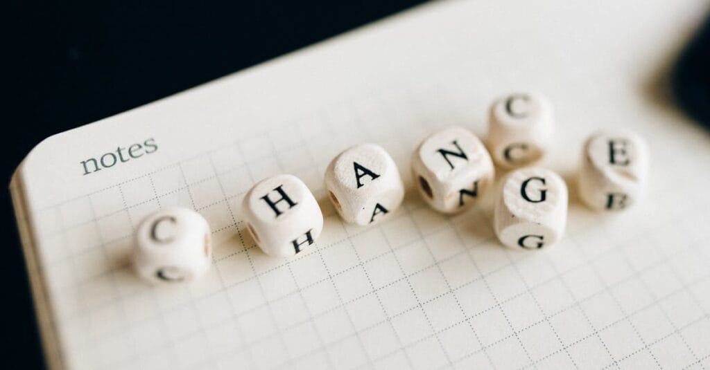 Close-up of letter dice spelling 'change' on a grid notepad, symbolizing transformation.