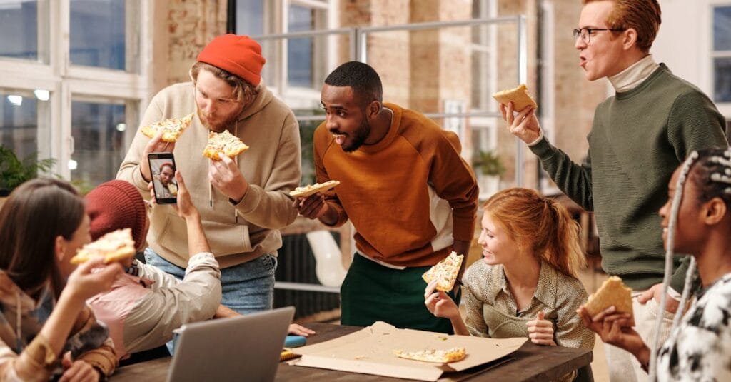 Colleagues having fun and eating pizza during an office break, capturing fun moments.