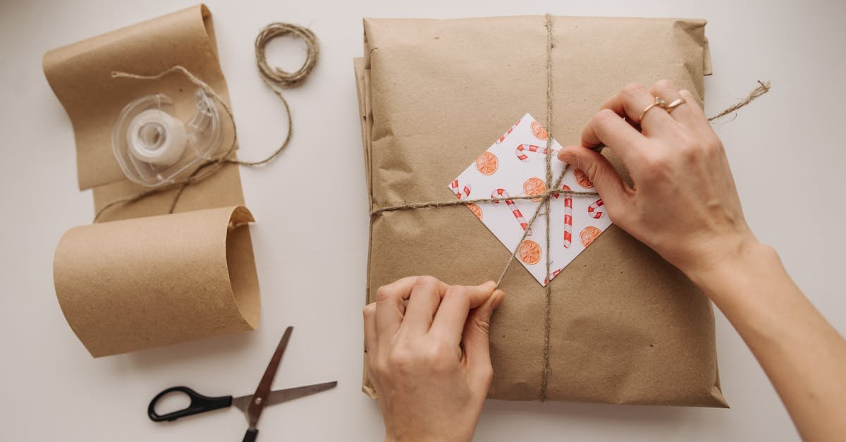 Hands tying a brown paper wrapped package with string, showcasing DIY gift wrapping.