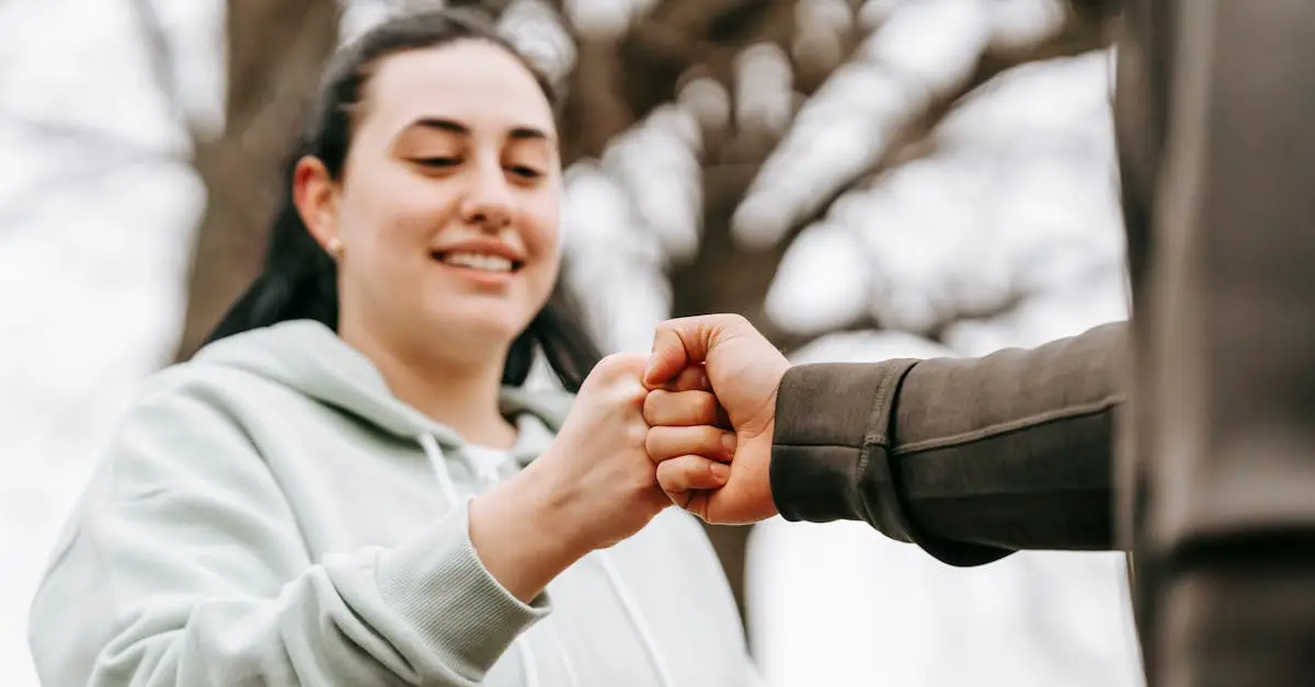 Two friends in casual wear sharing a fist bump outdoors, expressing friendliness and positivity.