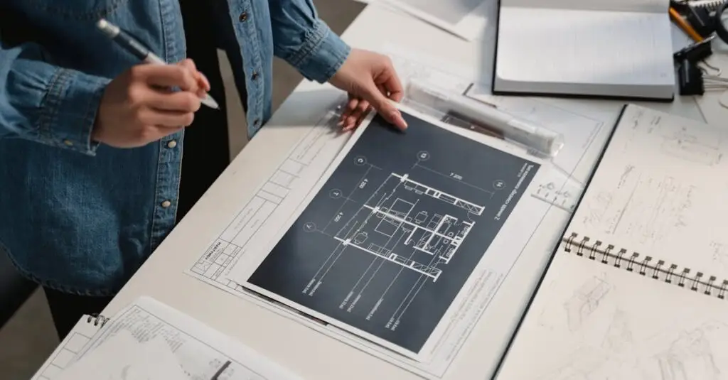 Engineer reviewing architectural blueprints on a desk with technical drawings.