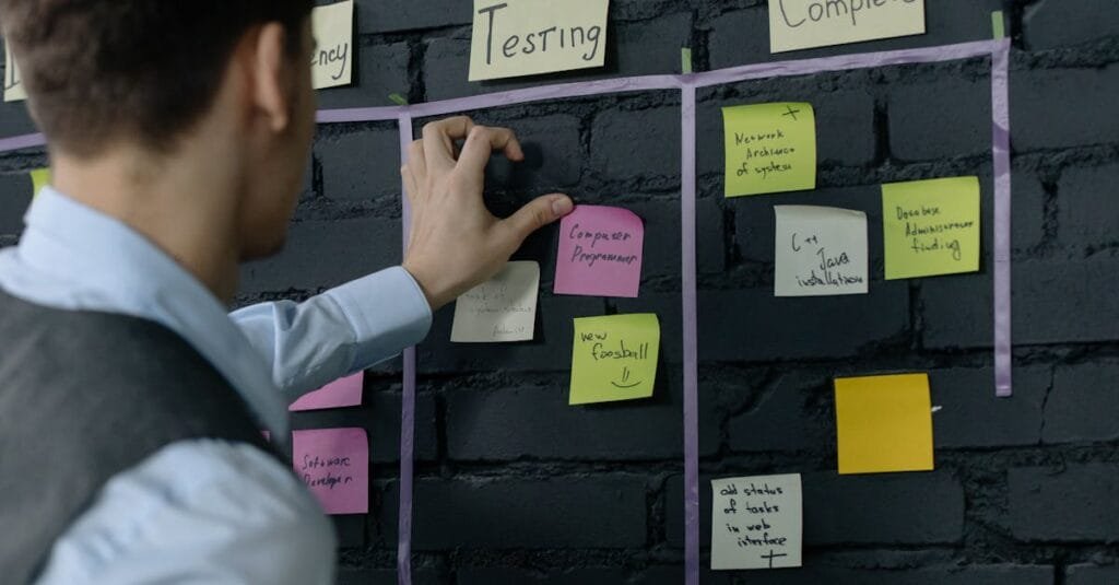 Man organizing project tasks on a wall using sticky notes in a modern office setting.