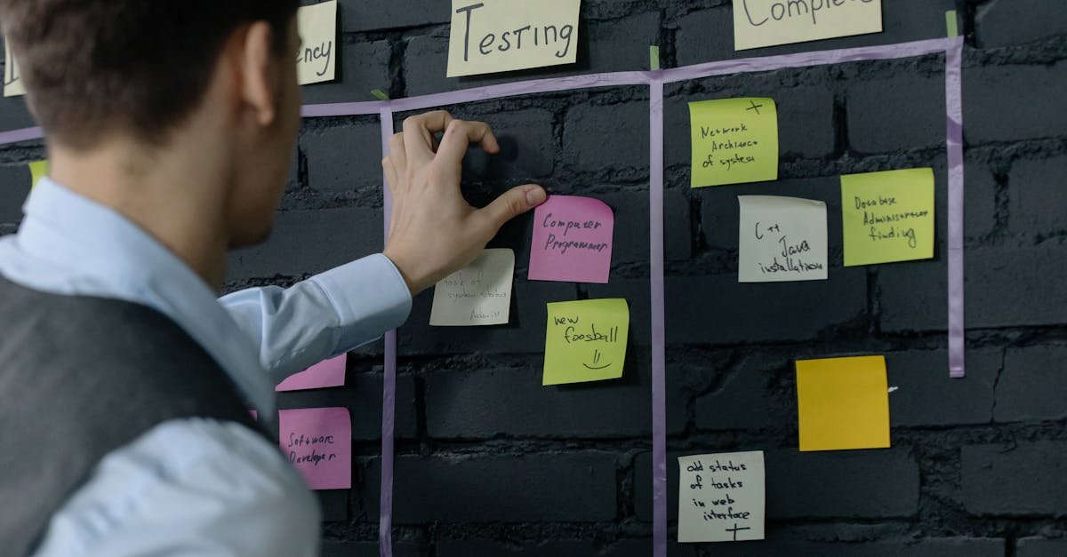 Man organizing project tasks on a wall using sticky notes in a modern office setting.