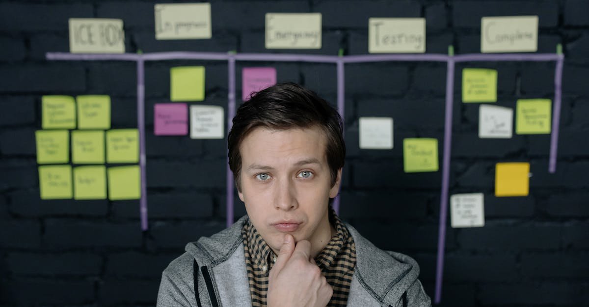 Pensive man in a startup workspace pondering tasks on a project board.