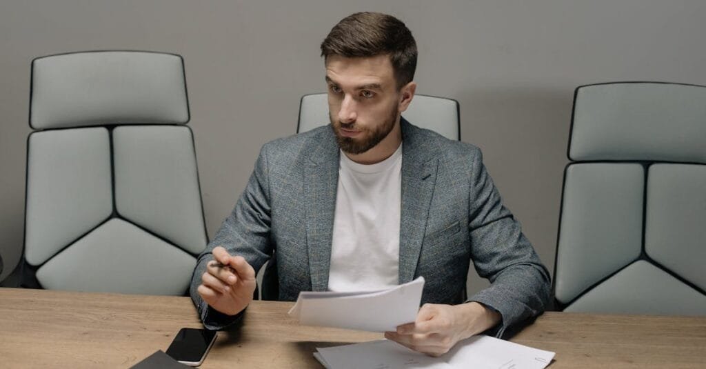 Professional businessman in a suit holding documents during a meeting in an office setting.