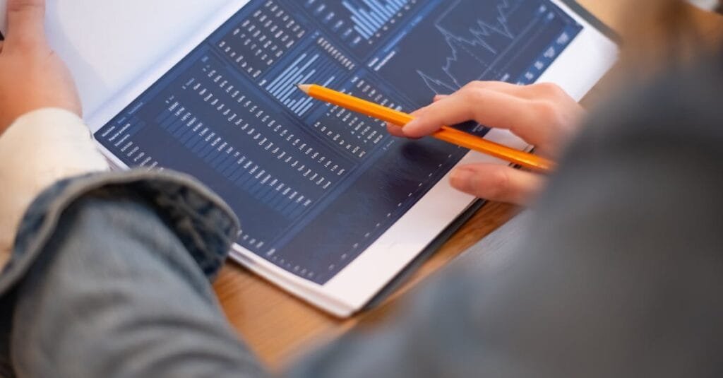 Focused image of hands analyzing business graphs and charts in a folder, highlighting data insights.