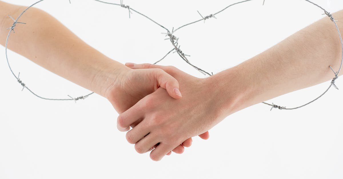 Symbolic handshake wrapped in barbed wire on a white background representing restriction and unity.