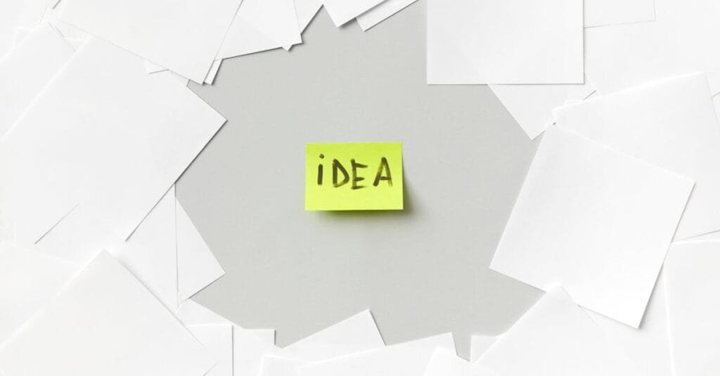 Yellow sticky note labeled 'Idea' surrounded by white papers, symbolizing creativity.
