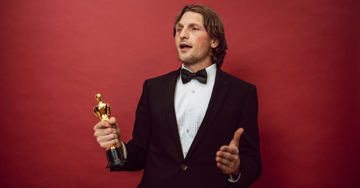 An accomplished man in a tuxedo holding a trophy, symbolizing triumph and recognition, against a red backdrop.