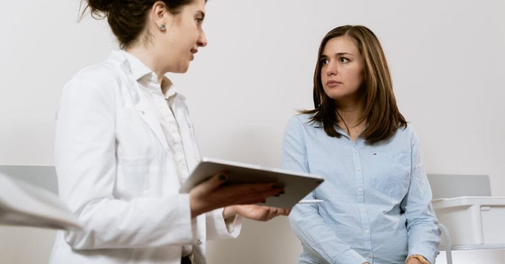 A doctor consults with a pregnant patient discussing healthcare options in a medical facility.