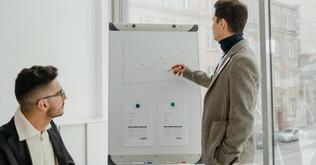 Two professionals examining graphs during an office presentation.