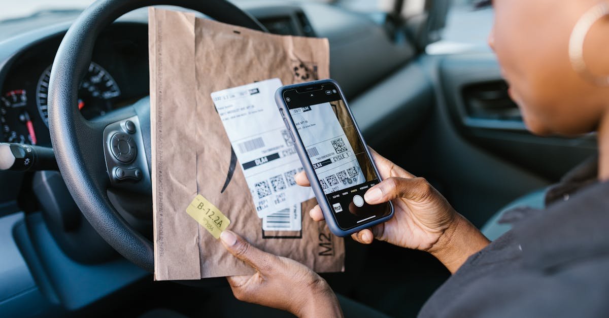 Close-up of a courier in a car scanning a package label with a smartphone for delivery service.
