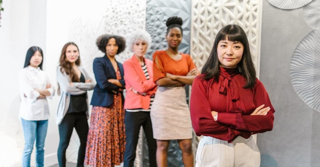 A diverse group of confident business women standing in a modern office setting.