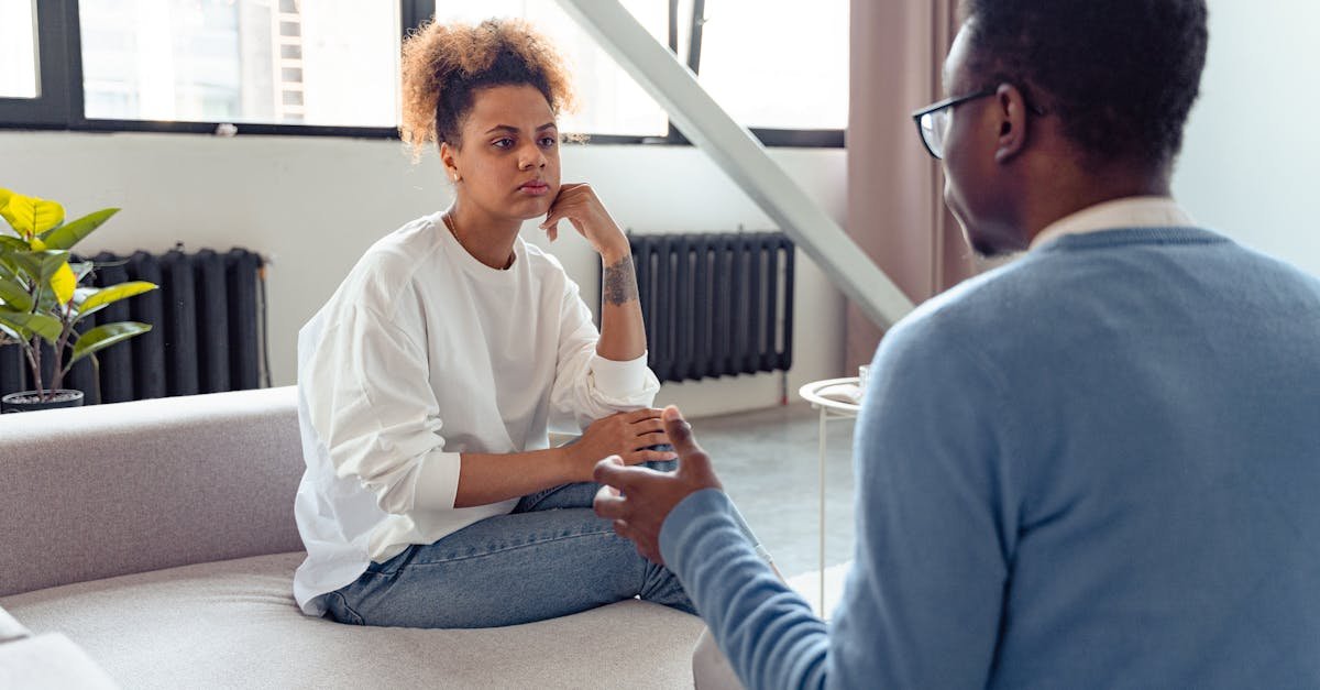 Two individuals engaged in a thoughtful therapy session indoors.