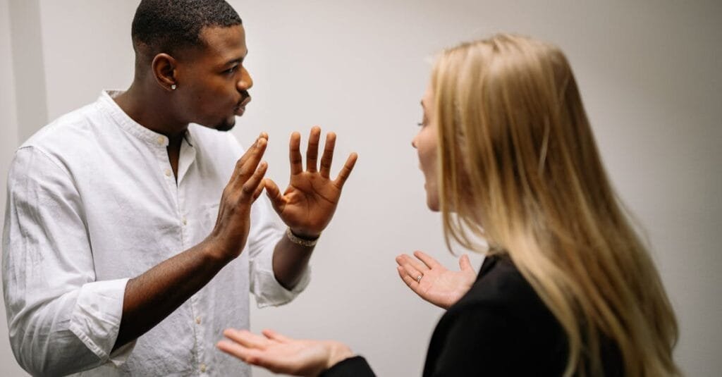 Frustrated coworkers in heated discussion, expressing disagreement in office setting.