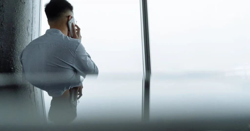 A professional making a phone call in a modern office setting with a city view.