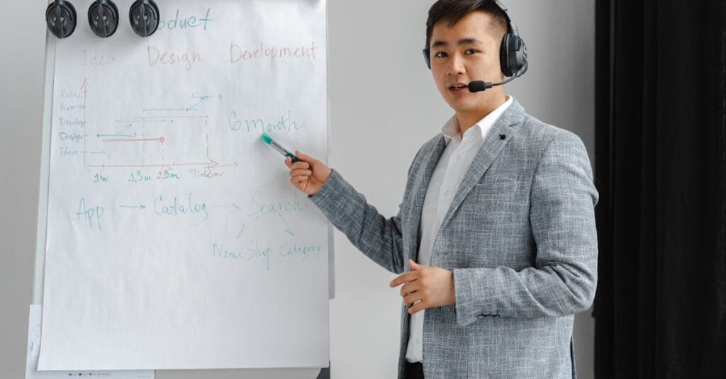 Asian man in a gray suit giving a presentation with a flipchart, wearing a headset.