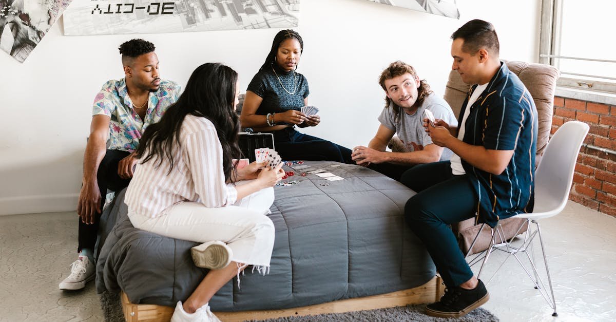 Group of college students enjoying a card game in a cozy dorm room setting.