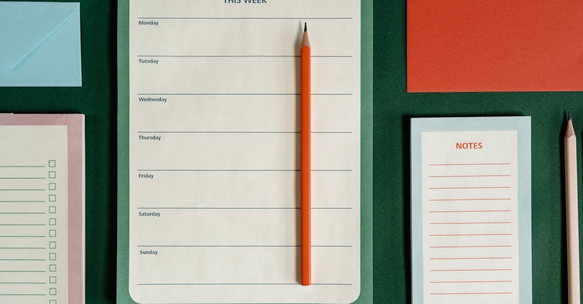 Flat lay of weekly planner, notes, envelopes, and pencils on a green background representing organization.
