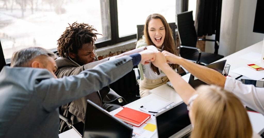 A diverse group of professionals celebrate a successful meeting with a fist bump.