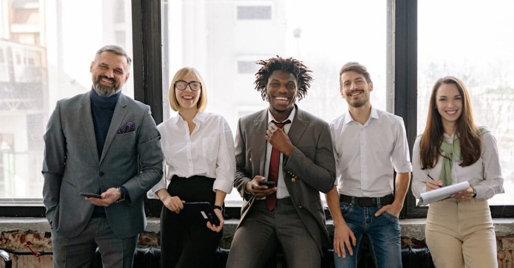 A diverse group of business professionals smiling and standing together in the office.