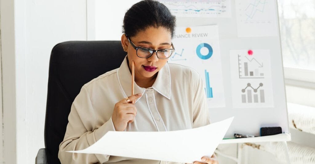 Businesswoman in glasses analyzing financial documents at her office desk.