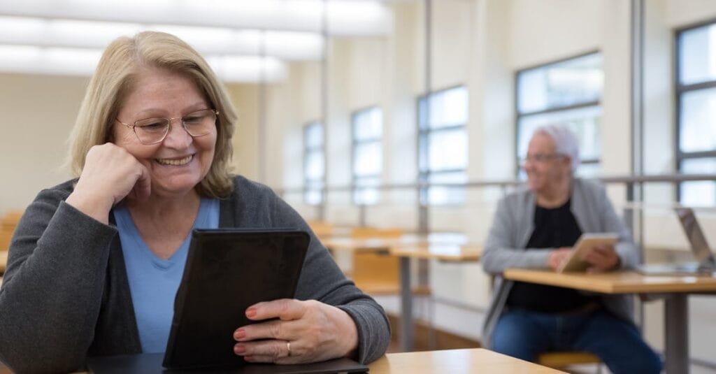 Senior adults learning to use tablets at a modern classroom in Portugal.
