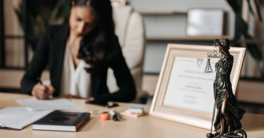 Focused woman writing at desk with Lady Justice figurine and certificate in office.