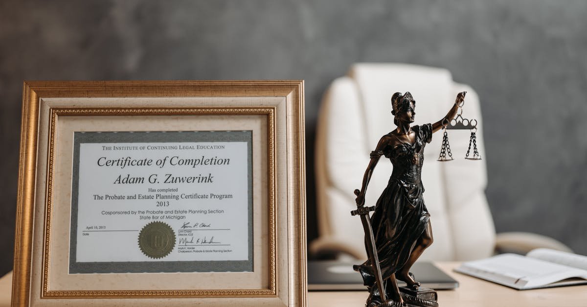 A framed legal certificate and Lady Justice figurine on a desk in a law office setting.
