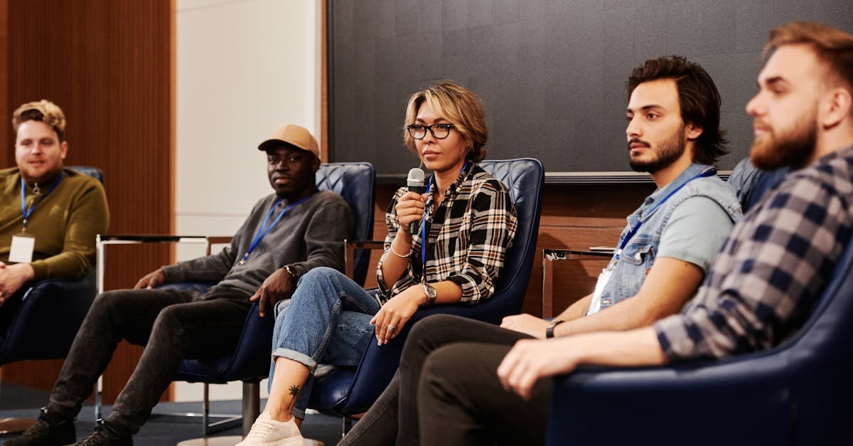 A diverse group of individuals engaged in an informative panel discussion at an indoor event.