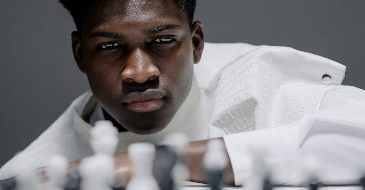 Focused young man playing chess, contemplating his next strategic move.