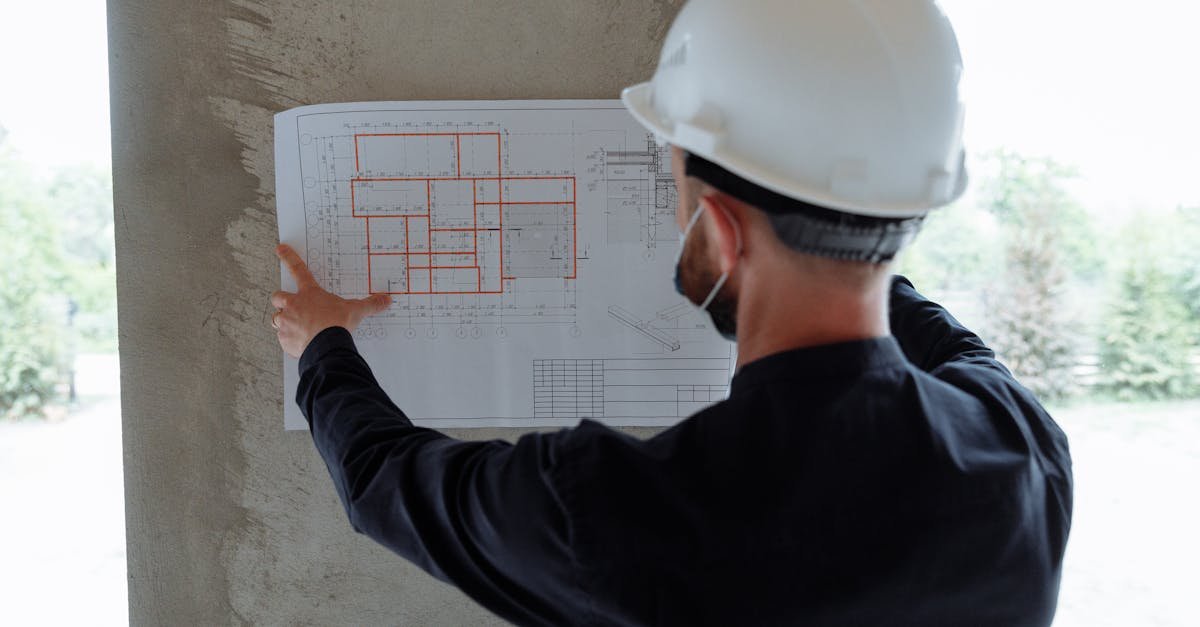Engineer in hardhat reviewing architectural floor plans at construction site.