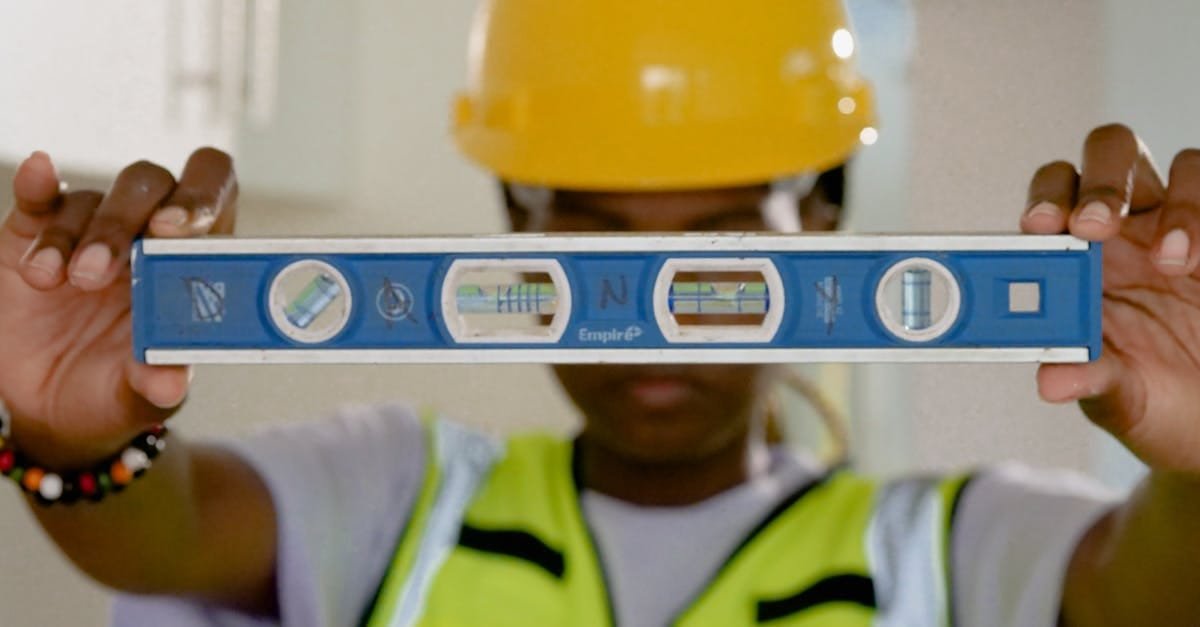 Close-up of construction worker holding a spirit level indoors.