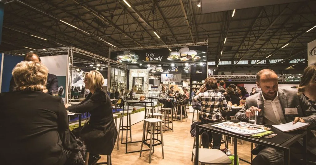 A bustling indoor business expo with professionals networking and engaging at various booths.