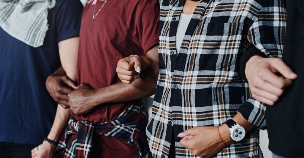Close-up of a diverse group of adults linking arms, symbolizing unity and solidarity.