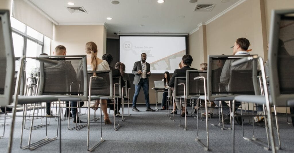 Business seminar with a diverse group, featuring a speaker in a modern conference room.