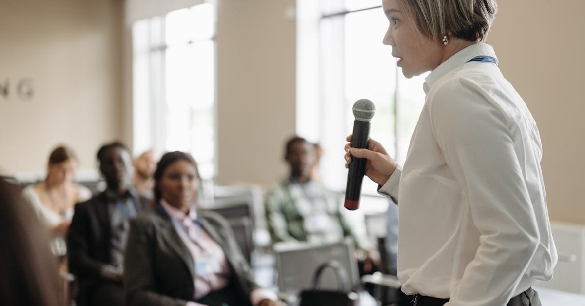 Side view of a businesswoman holding a microphone while addressing an audience at a conference.