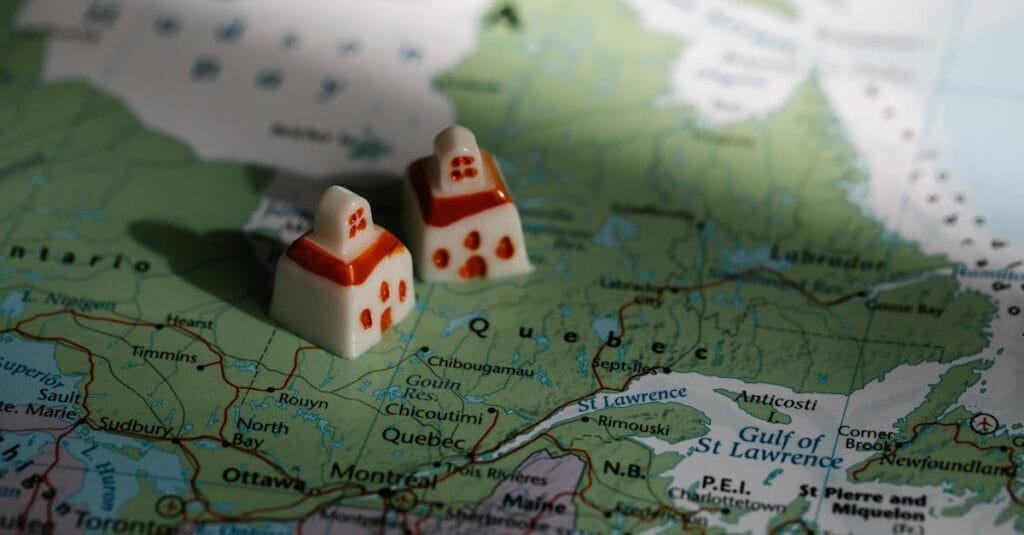 Close-up view of two miniature house figurines placed on a map of Quebec, Canada.