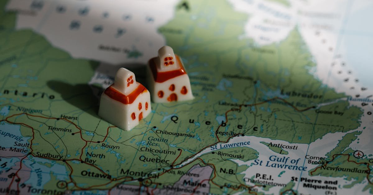Close-up view of two miniature house figurines placed on a map of Quebec, Canada.