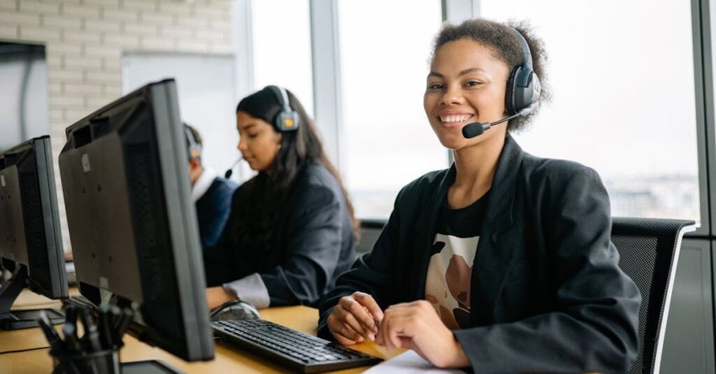 Smiling customer service representatives with headsets working in a bright modern office.