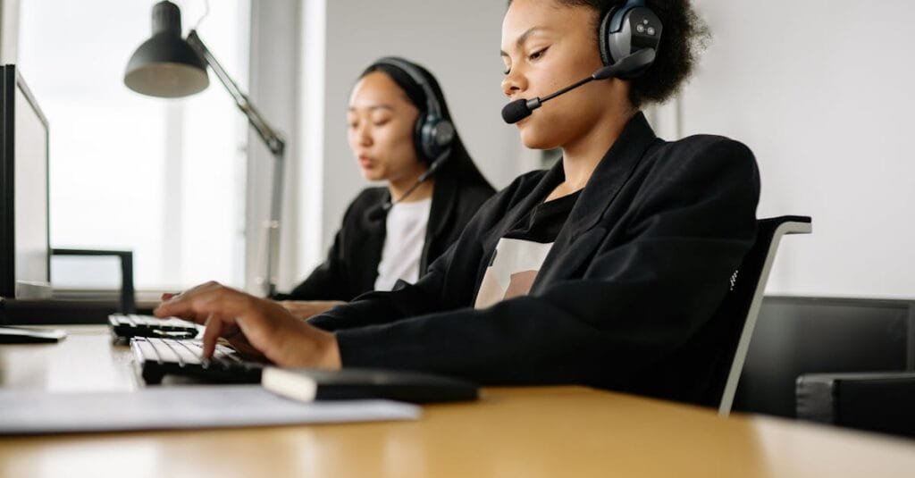 Two call center agents working at desks in an office setting with headsets.