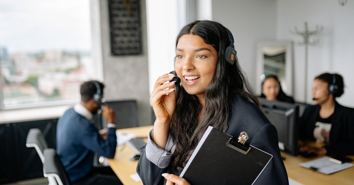 A smiling call center agent with headphones works in a modern office.