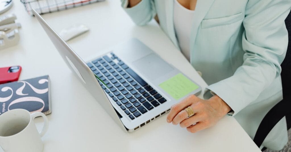 Businesswoman in office attire working on a laptop at a desk, symbolizing modern professional life.