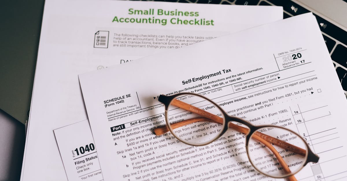 Close-up of tax forms and a small business accounting checklist on a laptop.