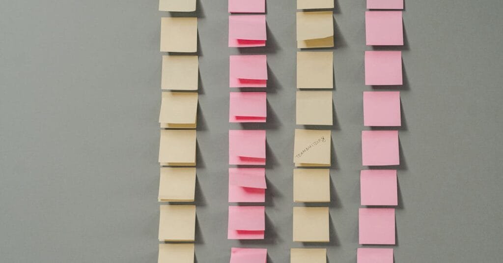 Rows of pink and yellow sticky notes on a gray background, ideal for planning concepts.