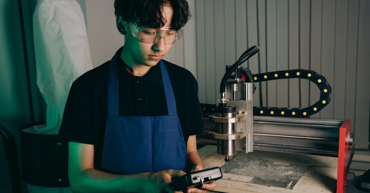 An engineer wearing safety glasses operates advanced machinery in a workshop setting.