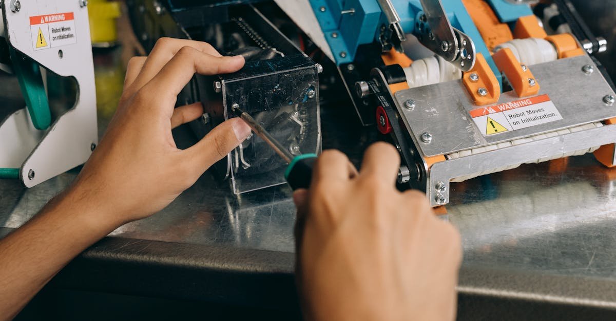 Hands of a technician repairing robotic machinery with precision tools on a workbench.