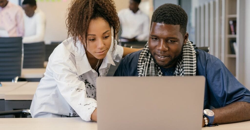 Two colleagues working together on a laptop in a contemporary office environment.