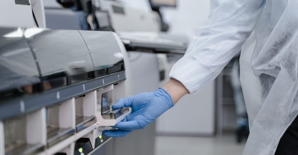 Lab technician in a white coat using equipment with precision in a sterile environment.